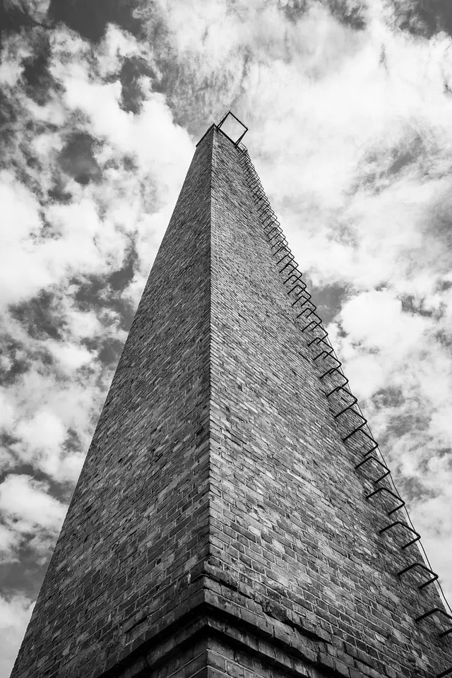 A dangerous looking ladder ascends the side of a tall tower